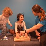Occupational therapy. Children's assessment. Child with headphones and hands in sand