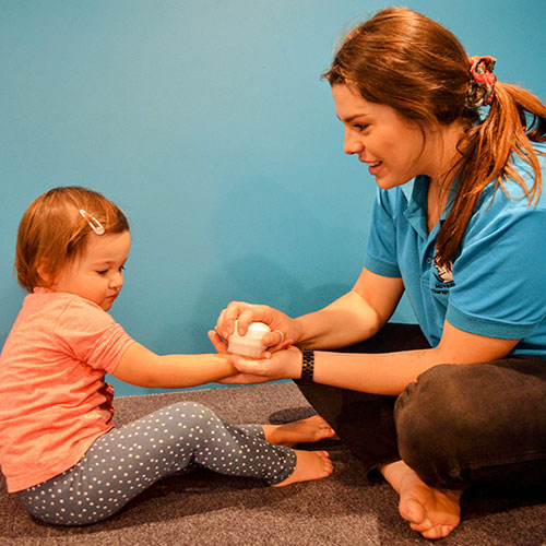 Therapist brushing child's hand with therapeutic brush