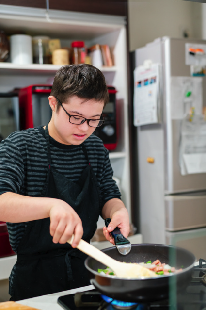 A young man cooks on a stovetop