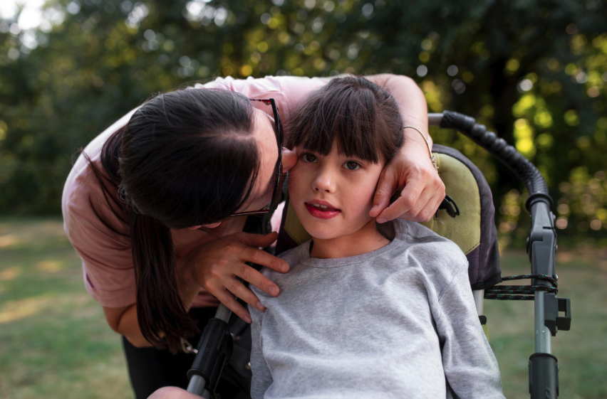 a mother and child at a park. The child sits in an adaptive stroller